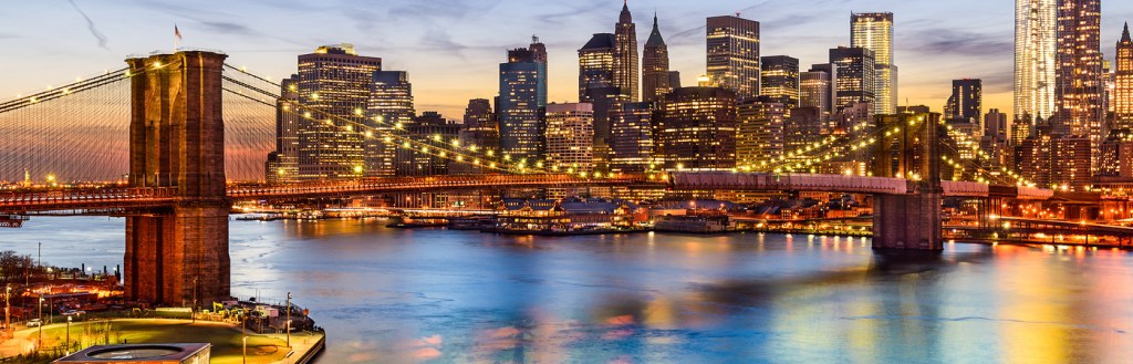 New York City, USA skyline over East River and Brooklyn Bridge.