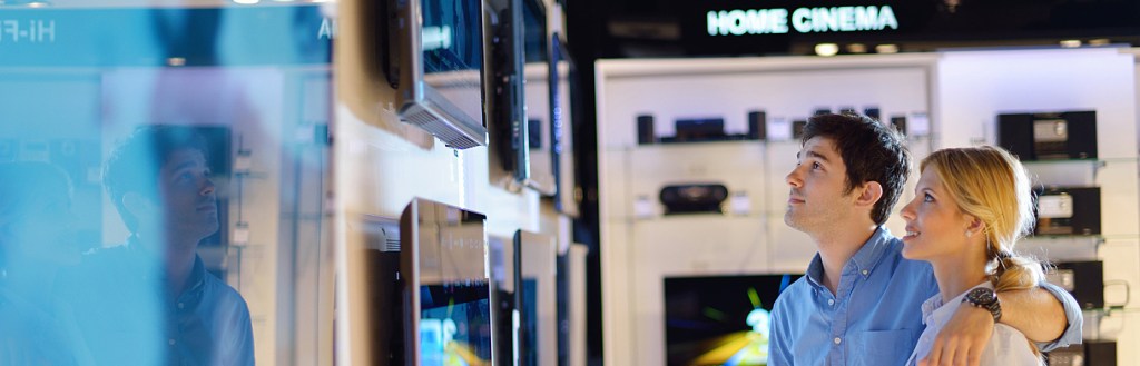 Young couple in consumer electronics store looking at latest lap